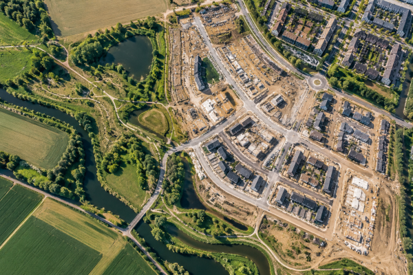 Luchtfoto van een woonwijk in ontwikkeling, omringd door bestaande bebouwing, infrastructuur, water en groen.